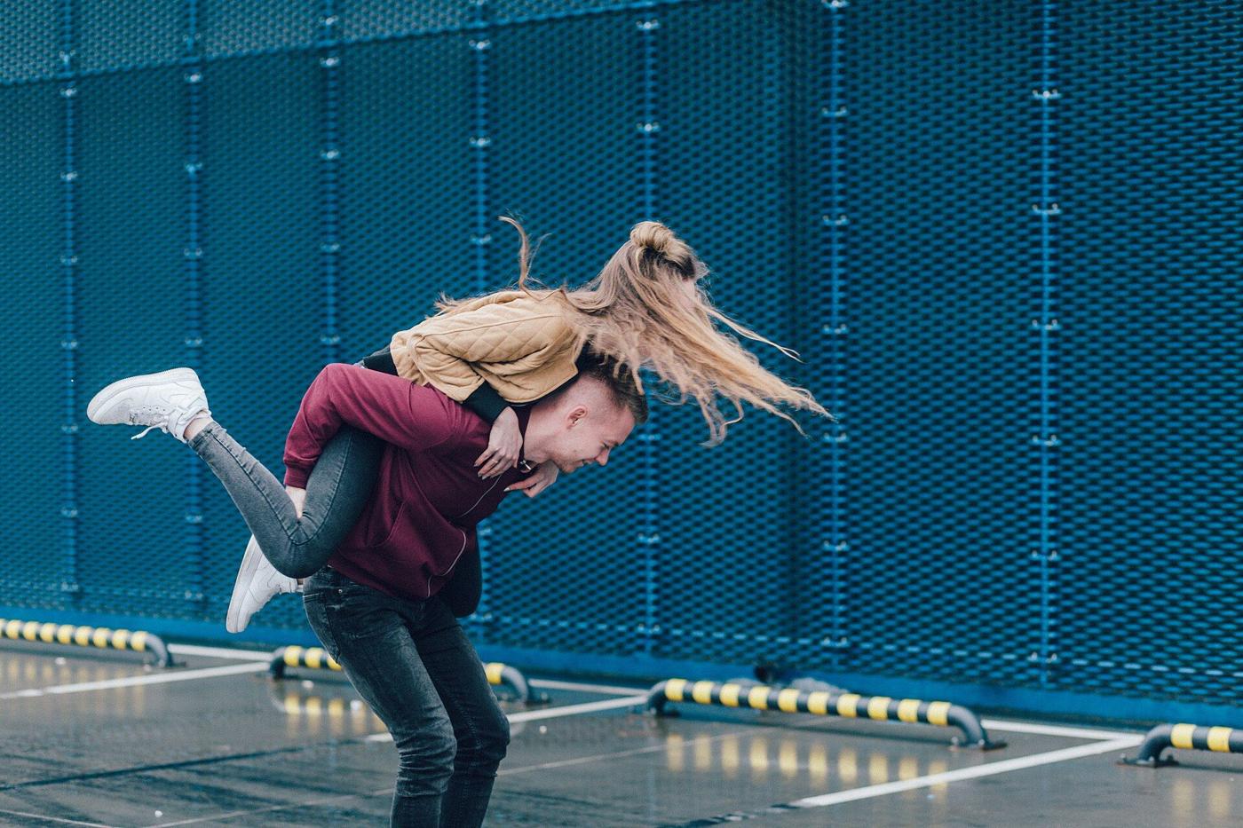 A couple playfully carrying each other on a city street
